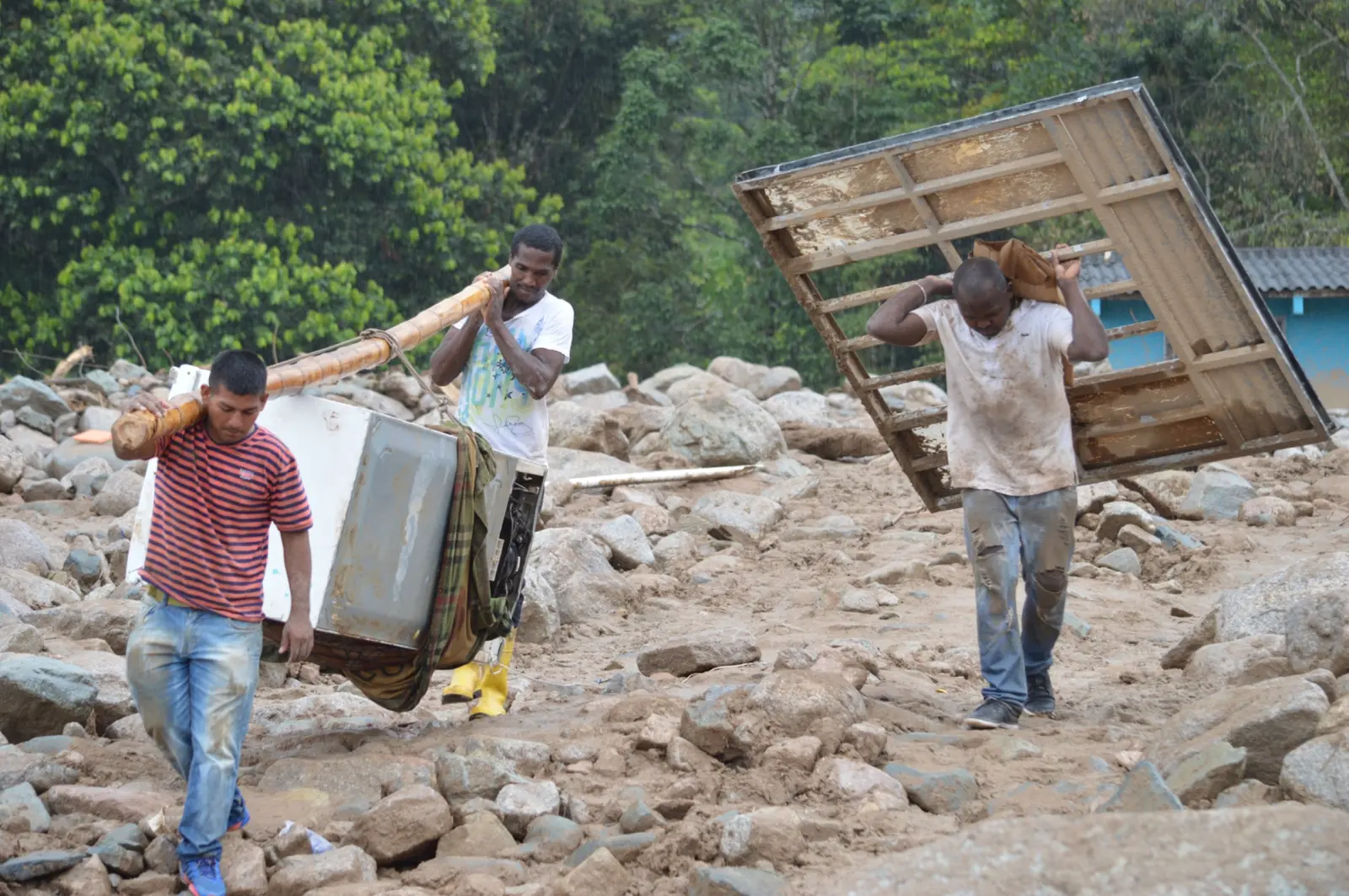 People carrying recovered materials through a damaged area