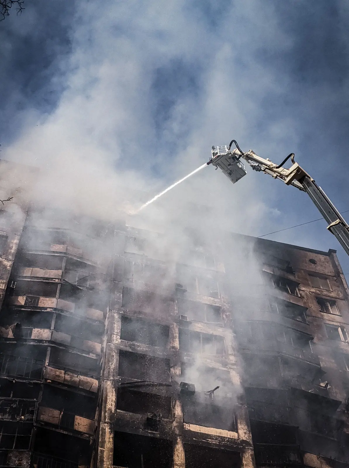 Firefighter directing water toward a smoke-filled building