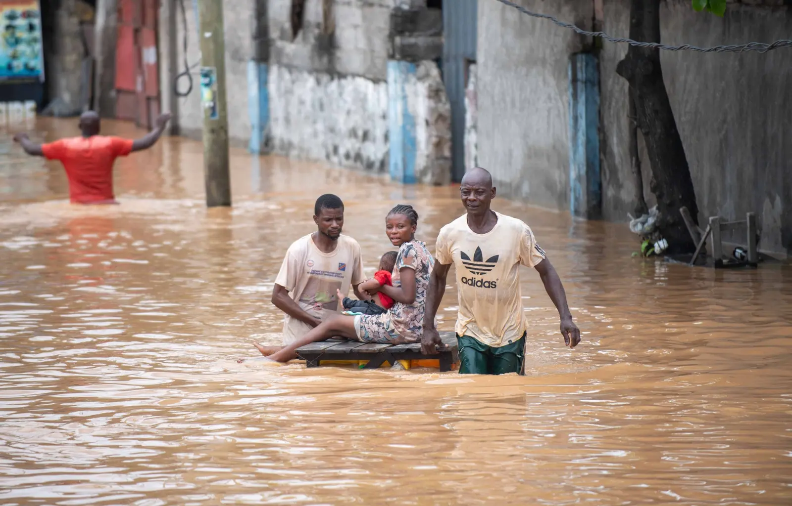 People carrying a child through deep floodwater