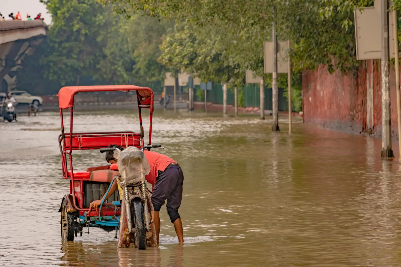 A three-wheeler travelling through a flooded street